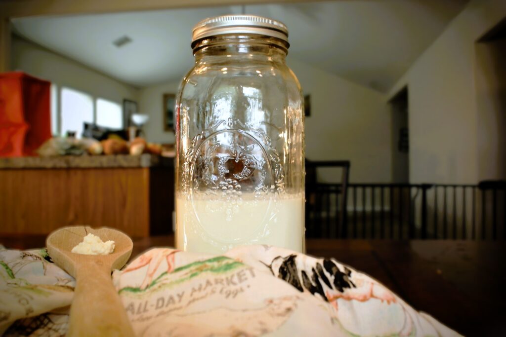 jar of milk kefir on counter with spoonful of kefir grains
